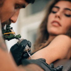 Young woman getting a tattoo on her arm