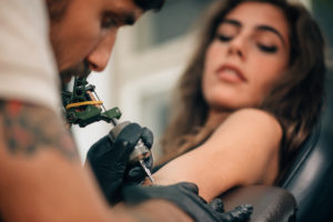 Young woman getting a tattoo on her arm