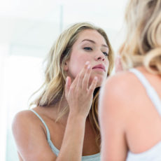 Woman looking in the mirror at her skin