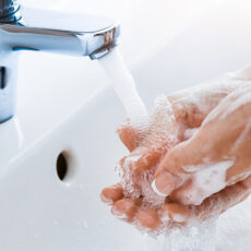 Woman uses soap to washing her hands under the sink faucet.