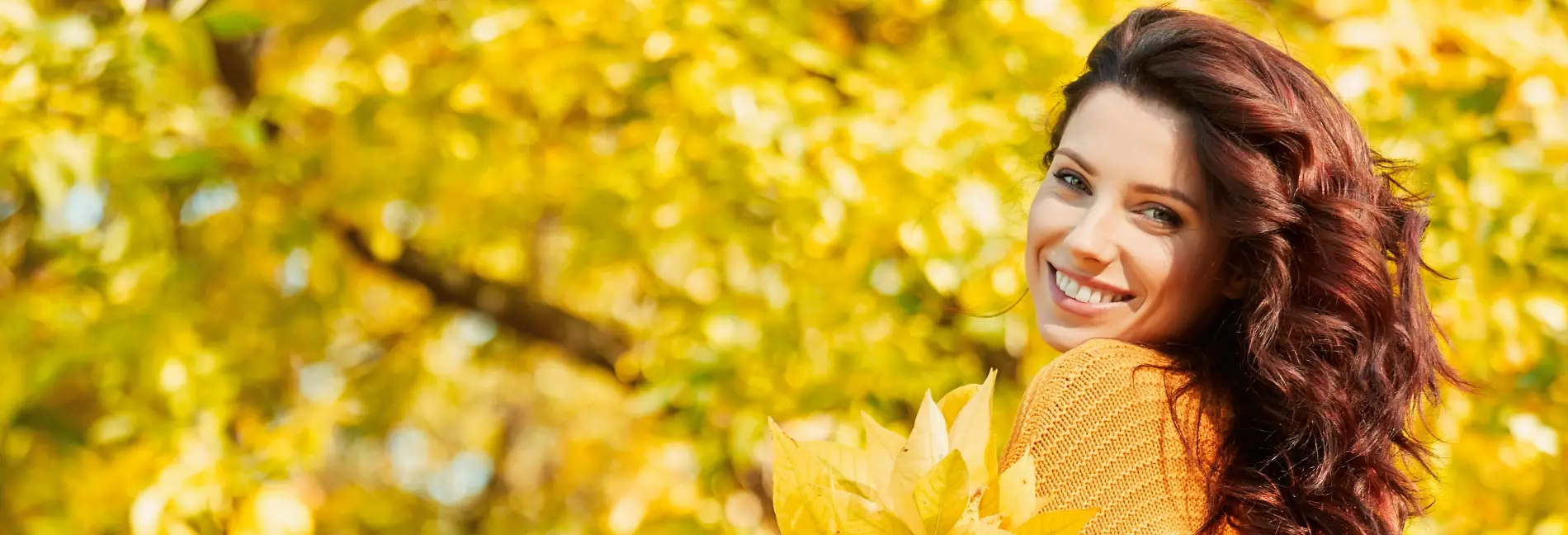 happy woman in autumn amongst the yellow leaves